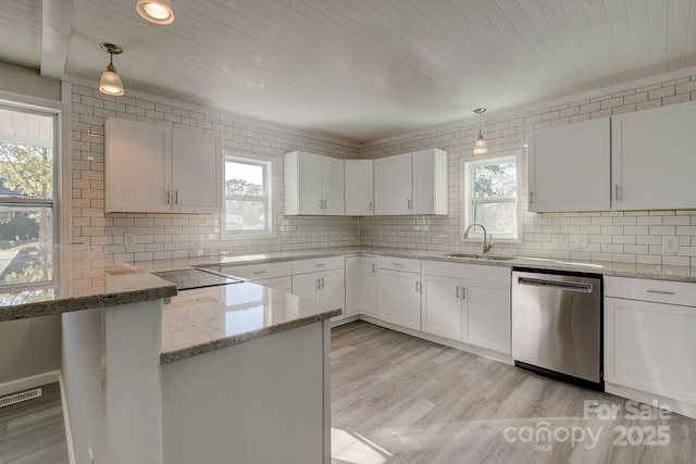 kitchen with stainless steel dishwasher, light wood finished floors, backsplash, and a sink