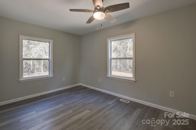 spare room with visible vents, baseboards, dark wood-type flooring, and ceiling fan