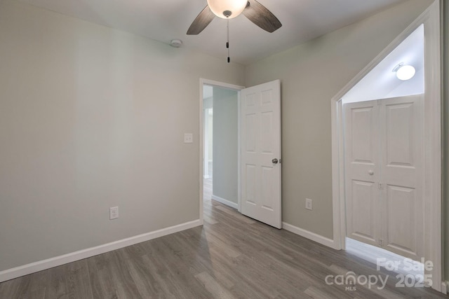 unfurnished bedroom with baseboards, wood finished floors, and a ceiling fan