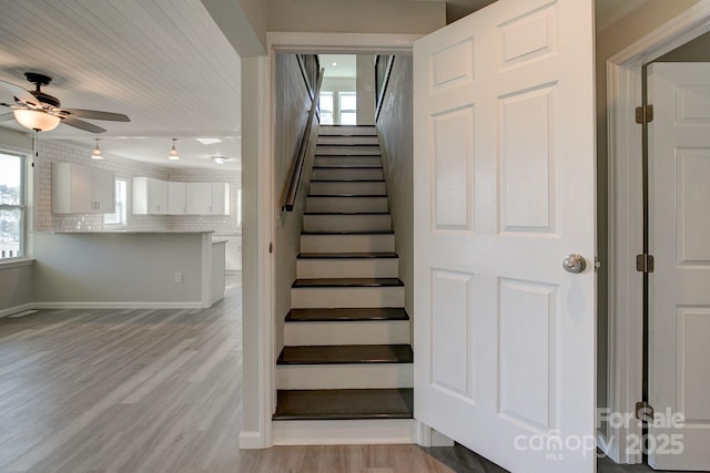 staircase with baseboards, wood finished floors, and a ceiling fan