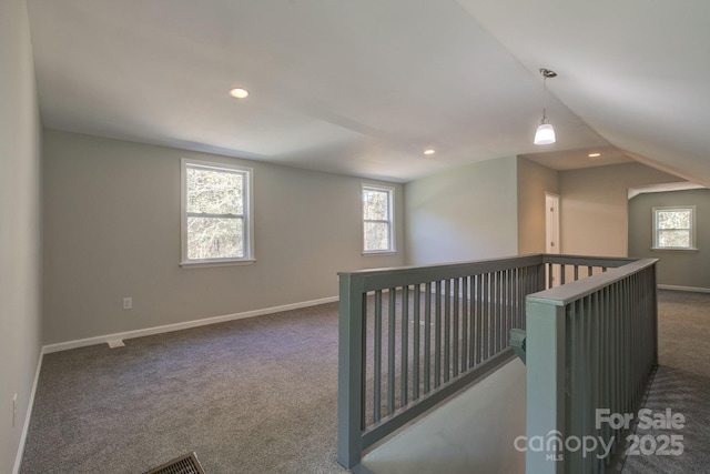 hall featuring carpet flooring, a healthy amount of sunlight, and an upstairs landing