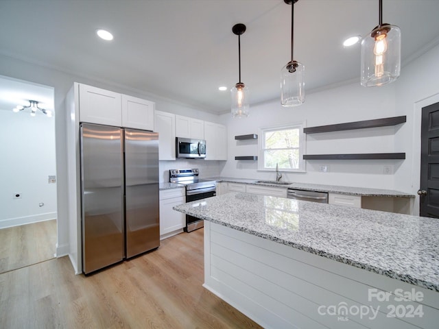 kitchen with white cabinetry, stainless steel appliances, pendant lighting, and light stone countertops