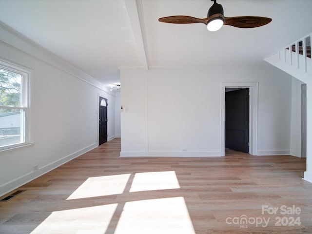 spare room featuring ceiling fan, light hardwood / wood-style floors, and beamed ceiling