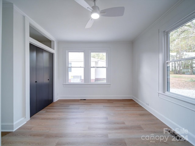 unfurnished bedroom with multiple windows, a closet, and light wood-type flooring