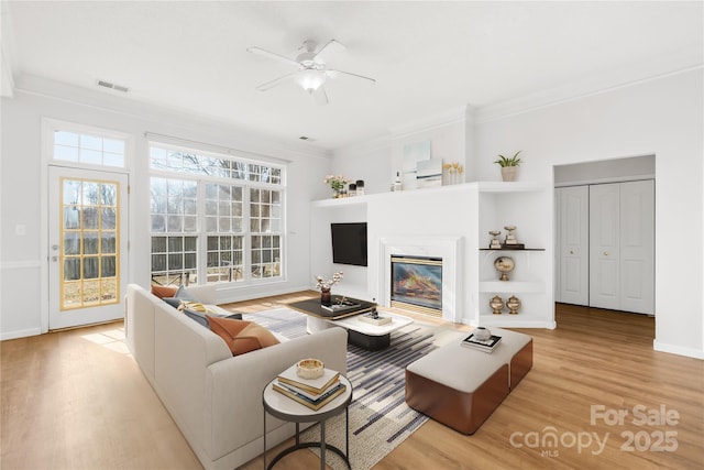 living room featuring light hardwood / wood-style flooring, ornamental molding, and ceiling fan