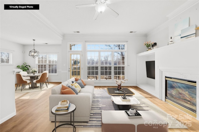 living room with crown molding, ceiling fan, and light hardwood / wood-style flooring