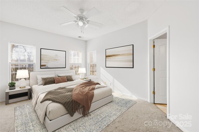 bedroom featuring light colored carpet, a textured ceiling, and ceiling fan