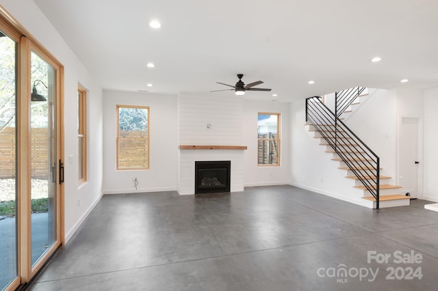 unfurnished living room with a large fireplace, a wealth of natural light, and ceiling fan