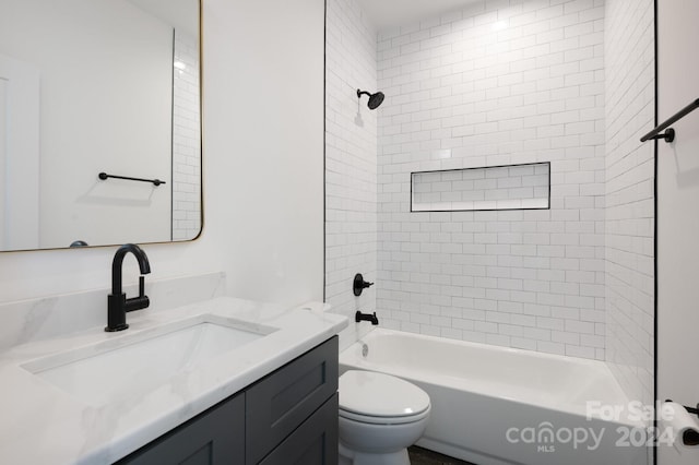 full bathroom featuring vanity, tiled shower / bath, and toilet