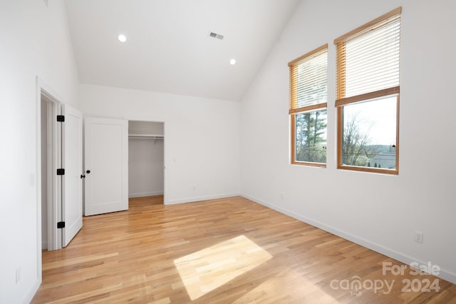 unfurnished bedroom with light hardwood / wood-style floors, lofted ceiling, and a closet