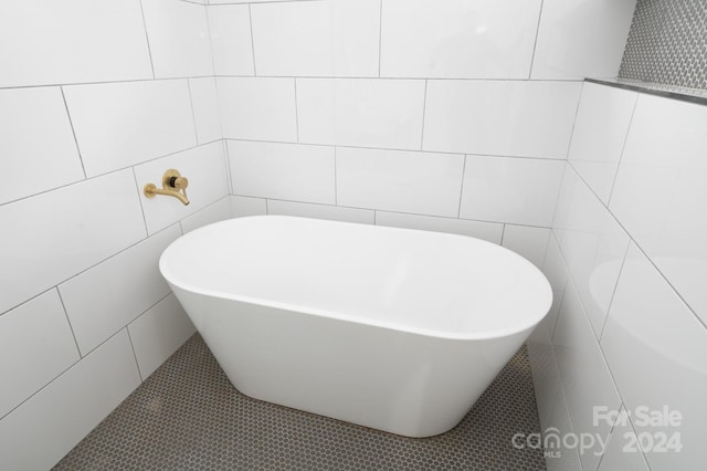 bathroom with a bathtub, tile walls, and tile patterned floors