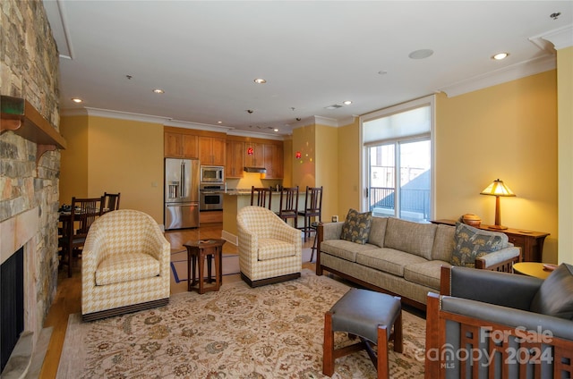 living room featuring ornamental molding, a fireplace, and light hardwood / wood-style floors