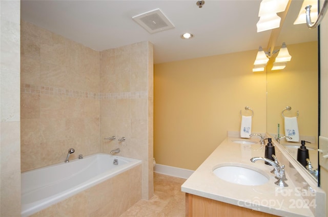 bathroom with tiled bath, tile patterned flooring, and vanity