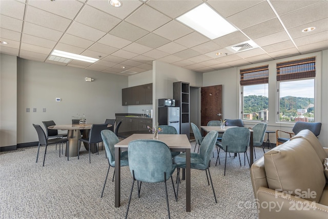 carpeted dining area with a paneled ceiling