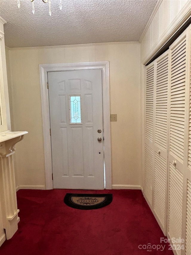 carpeted foyer featuring a textured ceiling