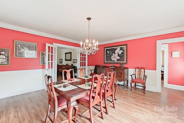 dining area with french doors, an inviting chandelier, ornamental molding, and hardwood / wood-style floors