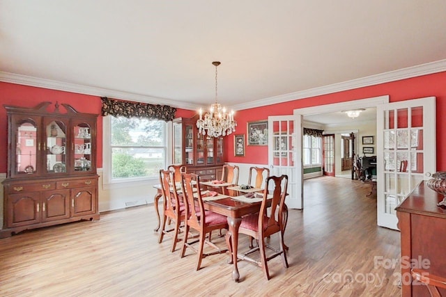 dining space featuring light hardwood / wood-style floors, ornamental molding, and a chandelier