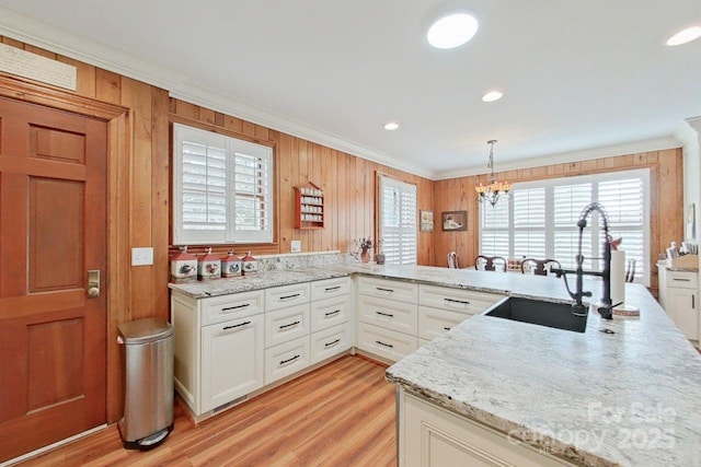 kitchen featuring an inviting chandelier, ornamental molding, white cabinets, and hanging light fixtures