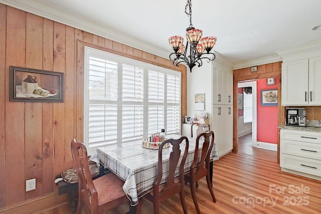 dining space with light wood-type flooring, a notable chandelier, and ornamental molding