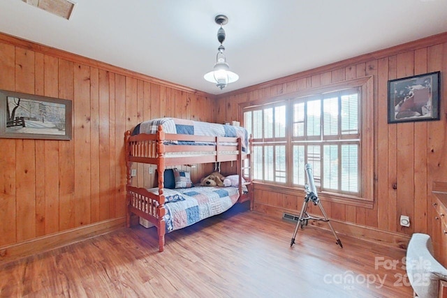 bedroom featuring light hardwood / wood-style flooring and wooden walls