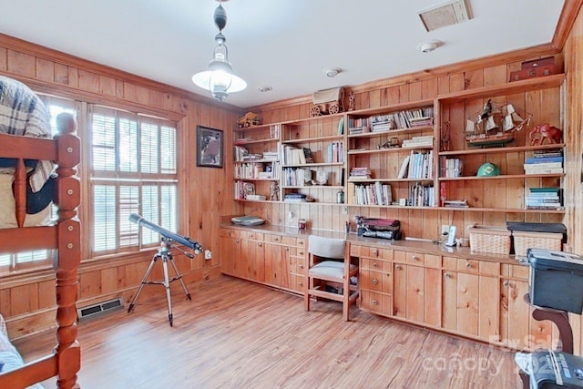 office area with light hardwood / wood-style floors, built in shelves, and wooden walls