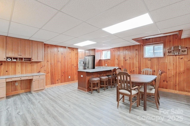 dining space featuring a drop ceiling and light hardwood / wood-style flooring