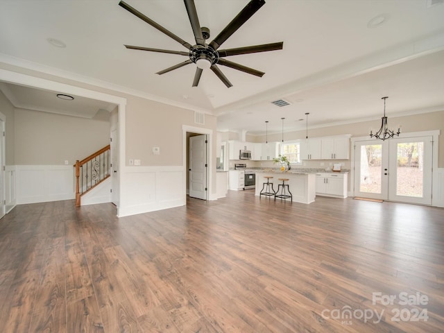 unfurnished living room featuring french doors, ceiling fan with notable chandelier, dark hardwood / wood-style floors, and ornamental molding