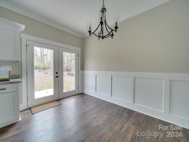 unfurnished dining area with crown molding, french doors, dark wood-type flooring, and an inviting chandelier