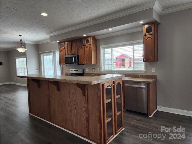 kitchen with dark hardwood / wood-style flooring, appliances with stainless steel finishes, crown molding, and hanging light fixtures