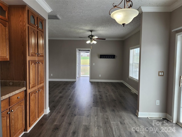 unfurnished dining area featuring dark wood-type flooring, a textured ceiling, ceiling fan, and crown molding