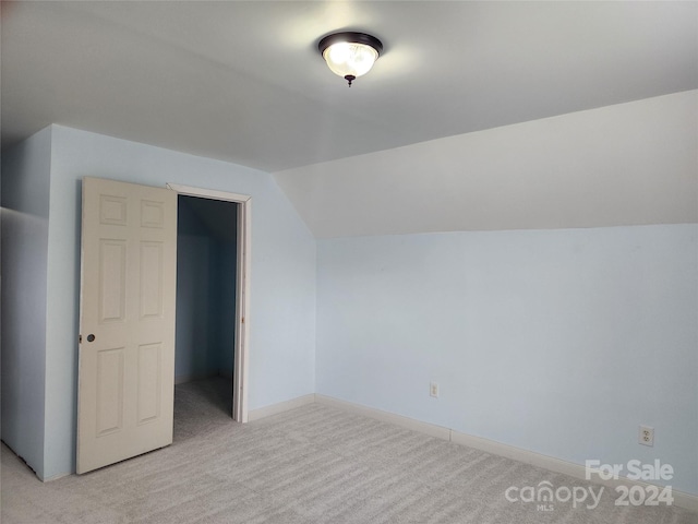 bonus room with lofted ceiling and light colored carpet