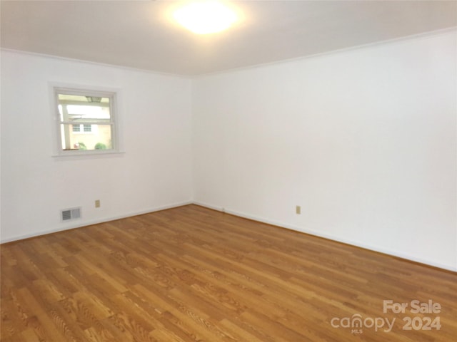 empty room featuring hardwood / wood-style flooring and ornamental molding