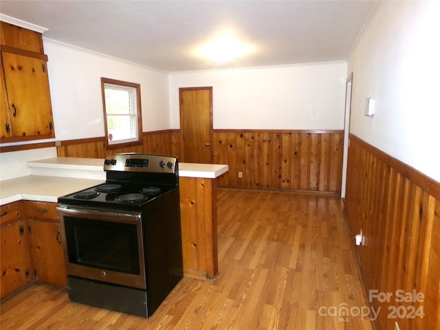 kitchen with ornamental molding, wood walls, stainless steel electric range oven, kitchen peninsula, and light hardwood / wood-style flooring