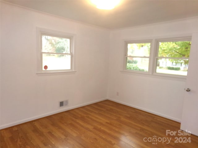 empty room featuring ornamental molding, plenty of natural light, and hardwood / wood-style flooring