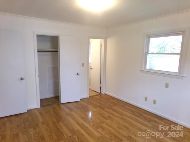 unfurnished bedroom featuring a closet, hardwood / wood-style flooring, and ornamental molding