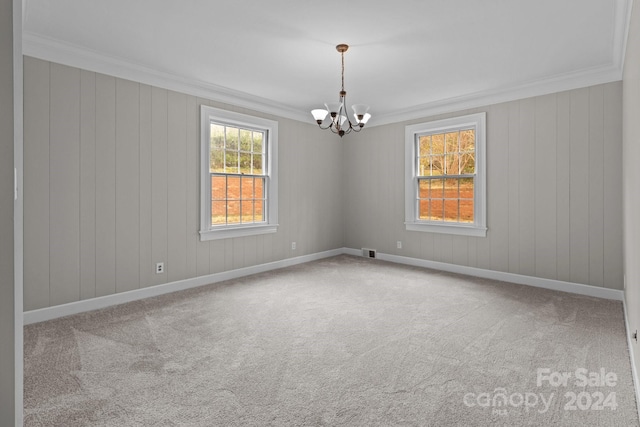 unfurnished room featuring a chandelier, carpet, wooden walls, and crown molding