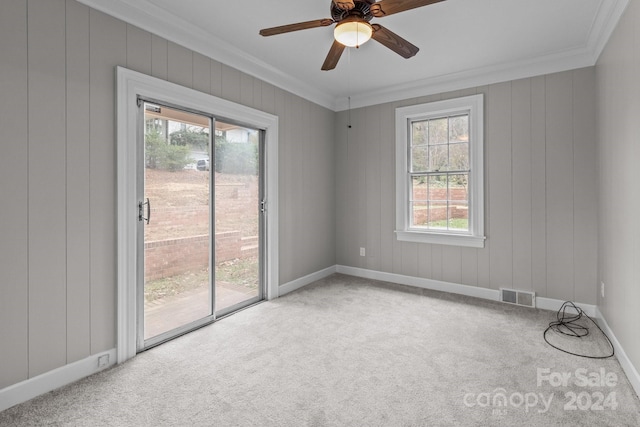 carpeted empty room with ceiling fan, plenty of natural light, and crown molding