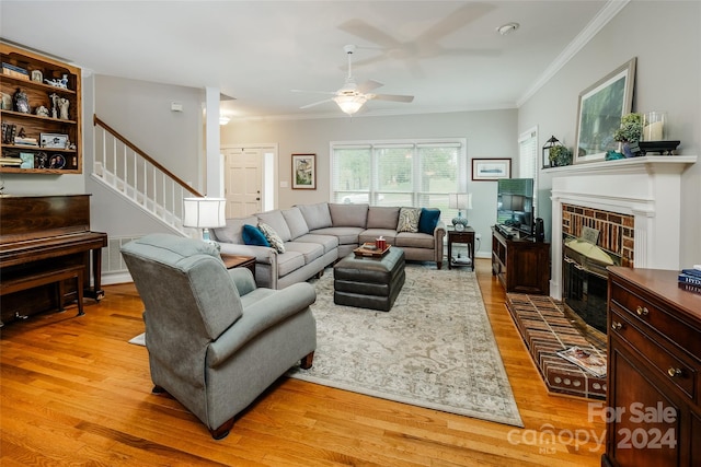 living room with a fireplace, ornamental molding, and light wood-type flooring