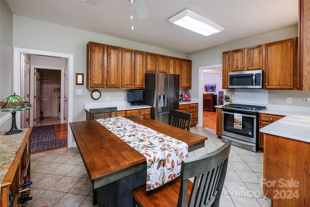 kitchen with ceiling fan, light tile patterned flooring, and stainless steel appliances