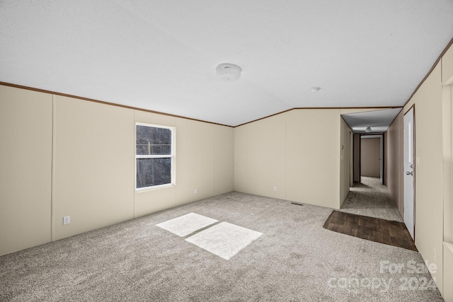 carpeted empty room featuring vaulted ceiling