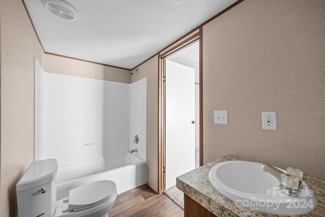 full bathroom with vanity, a textured ceiling, bathtub / shower combination, hardwood / wood-style flooring, and toilet