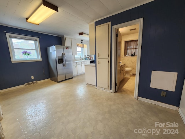 kitchen featuring ornamental molding, stainless steel fridge, and white cabinets