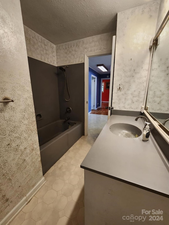 bathroom featuring tile patterned flooring, a textured ceiling, vanity, a skylight, and tub / shower combination