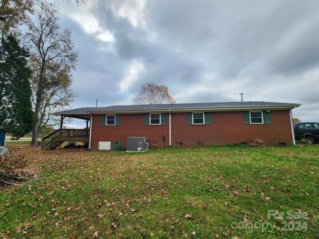 rear view of house featuring central AC unit, a lawn, and a wooden deck