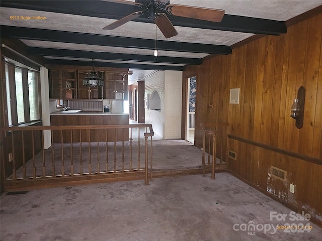 living room with beamed ceiling, wooden walls, and ceiling fan