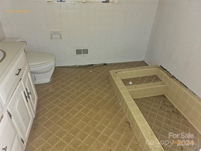 bathroom featuring tile walls, walk in shower, vanity, tile patterned flooring, and toilet