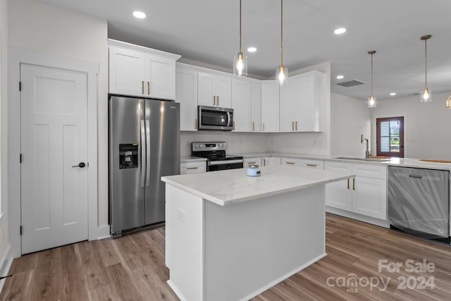 kitchen featuring sink, pendant lighting, light wood-type flooring, appliances with stainless steel finishes, and white cabinetry