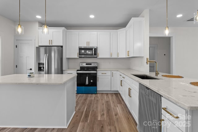 kitchen featuring hanging light fixtures, white cabinetry, stainless steel appliances, and sink