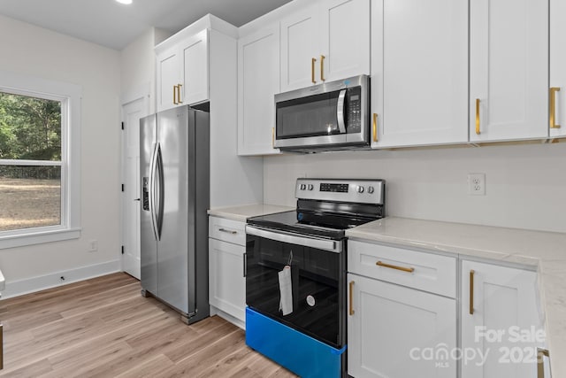 kitchen featuring white cabinets, appliances with stainless steel finishes, light stone counters, and light hardwood / wood-style flooring