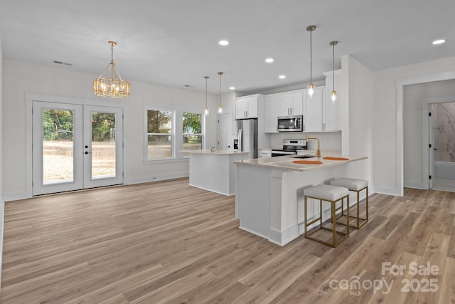 kitchen featuring white cabinetry, sink, appliances with stainless steel finishes, a breakfast bar area, and pendant lighting